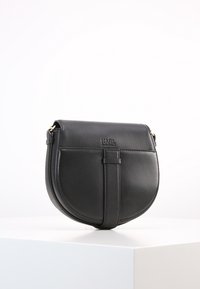 Borsa a tracolla in pelle nera con forma arrotondata, pattina anteriore e tracolla centrale. Caratterizzata da hardware color oro e dettagli con logo in rilievo.