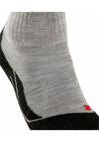 Szare i czarne skarpetki sięgające kostki z prążkowaną fakturą; posiadają czerwony akcent i biały wzór po boku, zaprojektowane z myślą o komforcie i dopasowaniu.
