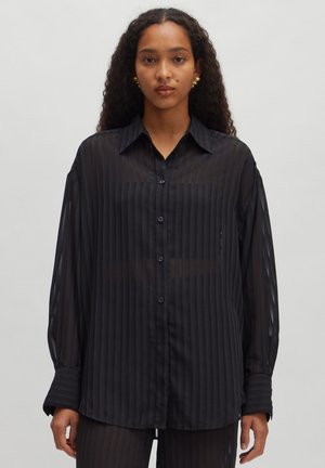 Chemise à manches longues à rayures noires, en matériau transparent, dotée d'un devant boutonné et d'un col classique. Agrémentée de boutons foncés.