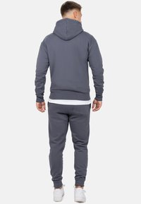Grijze hoodie en sweatpants set, gemaakt van zacht materiaal met ribgebreide boorden en tailleband, met een voork bolsillo en subtiel logo detail.