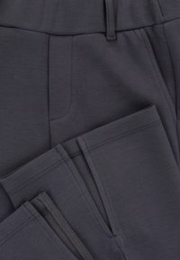 Donkergrijze broek gemaakt van zachte stof, met een gladde textuur, een platte tailleband en praktische zakken aan de voorkant met nette stiksels.