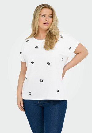 Weißes Baumwoll-T-Shirt mit verstreutem schwarzen Schleifenstickerei, Rundhalsausschnitt und kurzen Ärmeln, kombiniert mit dunkelblauen Jeans.