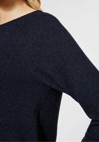 Pull en maille bleu marine avec un col rond, des manches longues et une texture douce, présentant un design sans coutures.