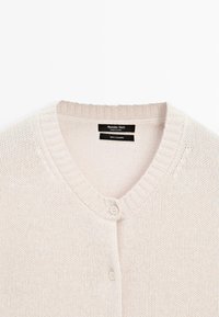 Cardigan in cashmere color crema con collo a costine e due bottoni, etichettato Massimo Dutti, prodotto in Cina.