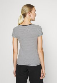 Tricou cu mânecă scurtă, dungi alb-negru, cu un decolteu rotund, design ajustat și textură netedă. Purtați-l cu pantaloni negri.