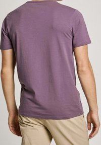 Lilla kortærmet t-shirt lavet af blødt stof, med rund hals og afslappet pasform, kombineret med lyse bukser.