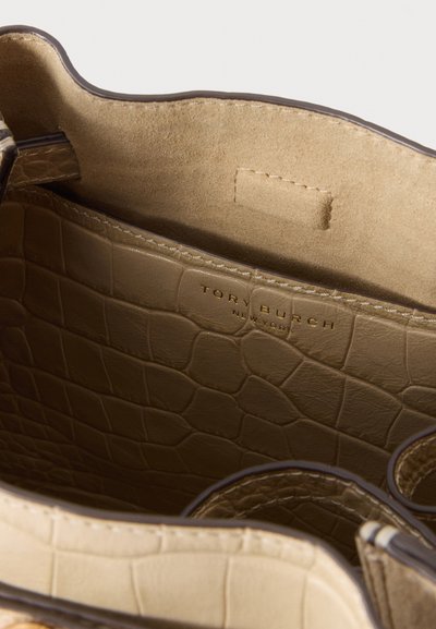 Εσωτερική όψη μπεζ δερμάτινης τσάντας Tory Burch με κροκό σχέδιο που δείχνει σουέντ επένδυση και ανάγλυφο όνομα της μάρκας.