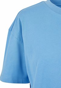 Jasnoniebieska koszulka z krótkim rękawem wykonana z bawełny, charakteryzująca się klasycznym okrągłym dekoltem i luźnym krojem z widocznymi detalami szwów.