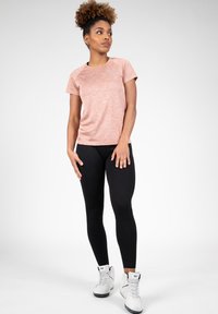 Lichtroze gemêleerde sport t-shirt, korte mouwen, gecombineerd met zwarte leggings en witte hoge sneakers. Eenvoudig ontwerp zonder patronen.