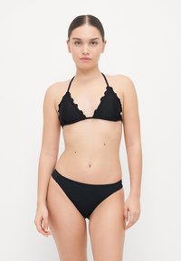 Black bikini with triangular top featuring ruffled edges, thin straps, and matching low-rise bottoms. Smooth, matte texture throughout.
