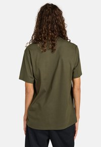Olive green short-sleeve t-shirt made of cotton. Simple design with a relaxed fit, featuring a straight hem and no patterns or embellishments.