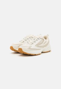 White athletic shoes with mesh and leather upper, rubber sole, and rubber outsole. Features a textured design and prominent laces.