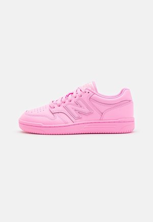 Rosa lädersneaker med rundad tå, perforeringar för andningsförmåga, platta skosnören och synligt "N"-märke på sidan. Texturerad sula.