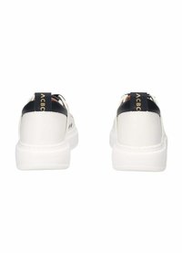 Zapatillas blancas con una parte superior lisa, acentos negros en el talón y branding dorado. Presentan una punta redondeada y una suela acolchada para mayor comodidad.