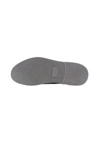Suela de zapato negra con una superficie texturizada de goma. Presenta una forma ovalada con un tacón plano y un pequeño parche rectangular cerca de la zona del dedo del pie.