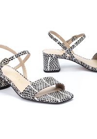 Sandalias de tacón de estampado de serpiente en blanco y negro con punta cuadrada, diseño de tiras cruzadas y un tacón bloque grueso para mayor estabilidad.