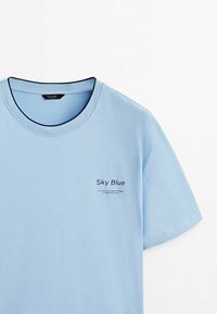 Himmelblå bomulds t-shirt med rund halsudskæring, korte ærmer og trykt tekst, der angiver "Himmelblå" og en beskrivelse nedenfor.