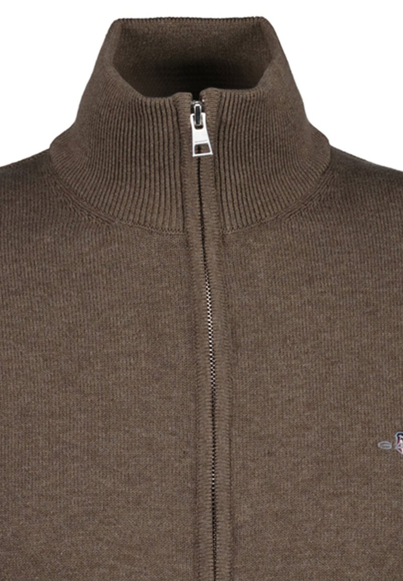 Brown knitted sweater with a high ribbed collar and a silver front zipper partially zipped up.