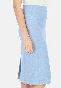Jasnoniebieska, teksturowana spódnica do kolan z bocznym rozcięciem i dopasowanym fasonem. Materiał ma subtelny wzór splotu, podkreślający dopasowany kształt.