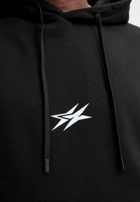 Czarna bluza z kapturem z białym logo błyskawicy na klatce piersiowej, z regulowanym kapturem i teksturowanym materiałem.