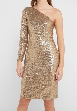 Gouden paillettenjurk met één-shoulder ontwerp en één lange mouw, nauwsluitend silhouet, knielengte zoom, gedragen door een vrouw tegen een effen achtergrond.