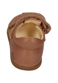 Brown leather shoe with a textured finish, featuring a rounded back, an adjustable strap, and a smooth interior lining.