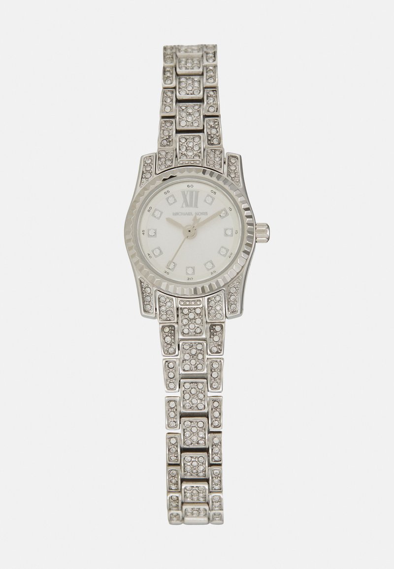 Reloj de pulsera plateado con correa texturizada y esfera redonda. Presenta acentos de cristal, el número romano XI y una esfera blanca con marcadores de horas.