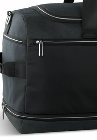 Bolsa de deporte negra con un tejido texturizado y un acabado suave y mate. Incluye cremalleras y acentos plateados para un almacenamiento seguro.