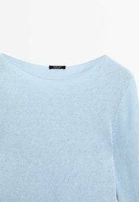 Pull en maille bleu clair avec un large col rond et des manches longues, avec une petite étiquette noire de la marque derrière le col.