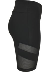 Pantaloni corti neri a vita alta realizzati in materiale elasticizzato, con un pannello in rete sul lato con accenti a strisce orizzontali.