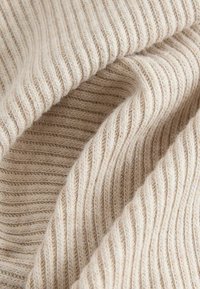Beige ribbattuoksi, joka tarjoaa pehmeän tekstuurin, vaihtelevilla koholla ja tasaisilla kuvioilla, esittelee herkän, neutraalin värimaailman.