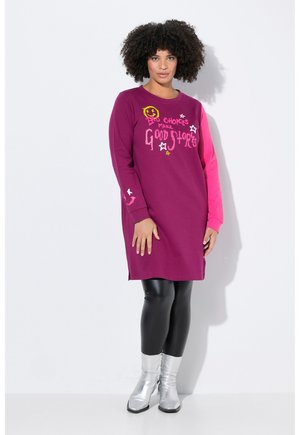 Robe longue magenta à manches longues avec des motifs de texte colorés et d'étoiles, accompagnée de leggings noirs et de bottes argentées brillantes.