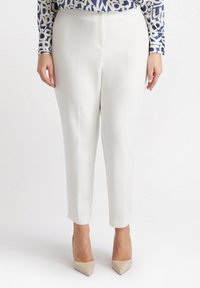 Witte op maat gemaakte broek met een zachte textuur, voorzien van voorkeursplooien en een kortere enkel lengte. Gekozen in combinatie met beige puntige hakken.