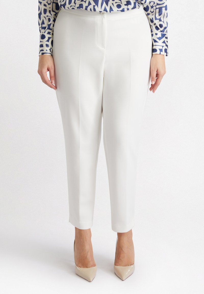 Witte op maat gemaakte broek met een zachte textuur, voorzien van voorkeursplooien en een kortere enkel lengte. Gekozen in combinatie met beige puntige hakken.