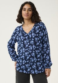 Marineblouse met een bloemenprint in lichtblauw, met een V-hals, lange mouwen en een iets gebogen zoom. Gemaakt van lichte stof.
