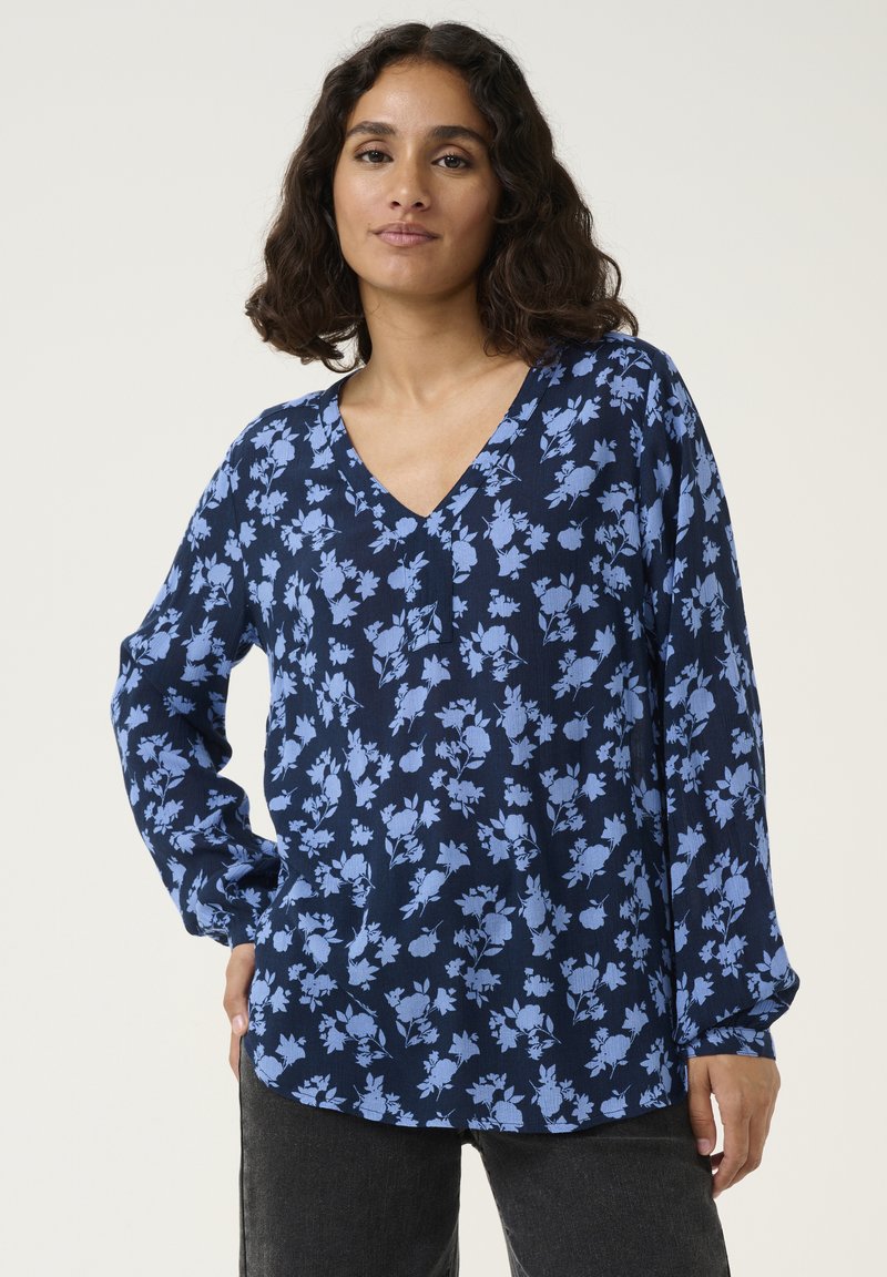 Marineblouse met een bloemenprint in lichtblauw, met een V-hals, lange mouwen en een iets gebogen zoom. Gemaakt van lichte stof.