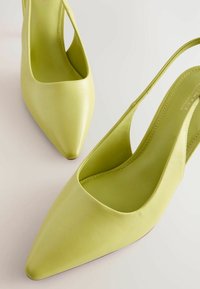 Simító orrú, világos zöld bőr slingback cipők, bemetszéses dizájnnal és karcsú sarokkal.