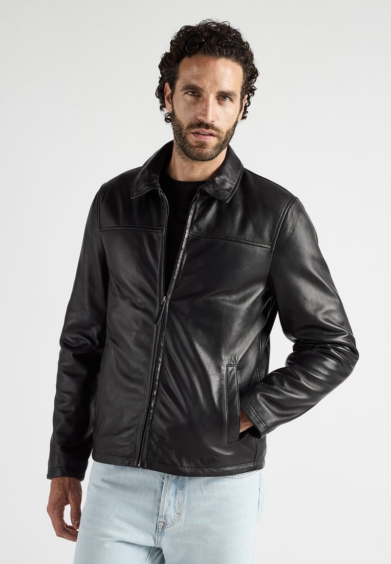 Zwarte leren jas met een kraag, gladde textuur, voorzakken en een ritssluiting, gecombineerd met lichtblauwe denim jeans.