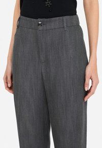 Pantaloni grigi su misura realizzati in tessuto testurizzato, dotati di chiusura a bottone, passanti per cintura e tasche laterali.