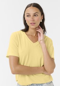 Gul kortærmet V-hals T-shirt lavet af blødt stof, med en afslappet pasform og en glat tekstur, parret med lyse denim-bund.