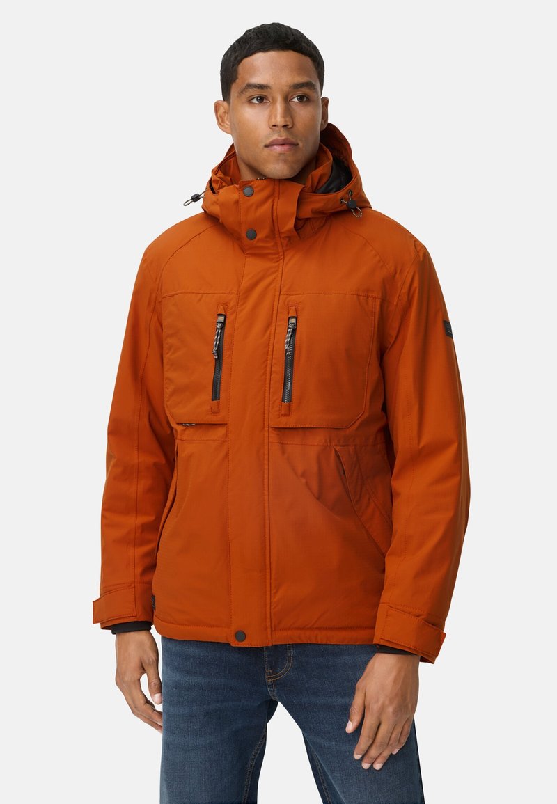 Pomarańczowa, ocieplana kurtka z kapturem, z zamykanymi na zamek kieszeniami na piersi, bocznymi kieszeniami oraz regulowanymi mankietami. Gładka tekstura i zorganizowany design.