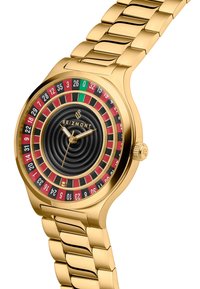 Gullfarget armbåndsur med en svart spiralurskive. Har fargede roulette-lignende markeringer i rødt, grønt og svart. Designet med metall lenkebånd.