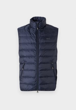 Granatowa kamizelka puchowa z wysokim kołnierzem, zamek błyskawiczny z przodu i dwiema bocznymi kieszeniami. Pikowany wzór z gładkiego, błyszczącego materiału oraz logo GANT na klatce piersiowej.