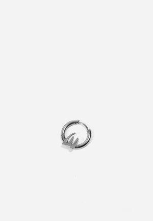 Les boucles d'oreilles en argent ont un design courbé et angulaire. Texture lisse avec un accent stylisé proéminent au centre.