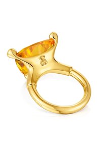 Złoty pierścionek z dużym fasetowanym kamieniem bursztynowym, trzymanym przez cztery pazurki, z małym detalem w kształcie niedźwiedzia na oprawie.