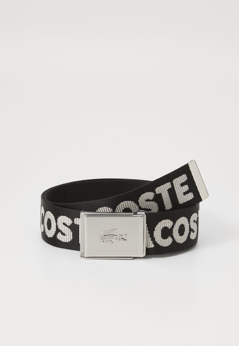 Ceinture tissée noire avec le texte "LACOSTE" en blanc, boucle en métal avec logo crocodile embossé et texture lisse.