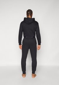 Zwarte hoodie en sweatpants outfit, met een zachte textuur, een relaxte pasvorm, manchet mouwen en enkels, en een logodetail op de tailleband.