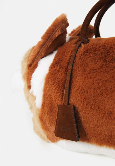 Geantă puf rezultată dintr-un amestec de culori maro și alb, având forma unui corgi, cu o textură din blană artificială, mânere din piele și un etichetă cu "MOSCHINO."
