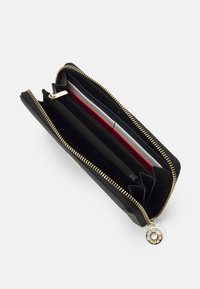 Portafoglio nero con zip in metallo dorato, dotato di molteplici slot per carte, una tasca con zip per le monete e una finitura liscia e testurizzata.