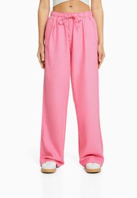 Pantalones ligeros de pierna ancha en tela rosa brillante con una cintura elástica y cordón ajustable. Textura suave, detalle mínimo.